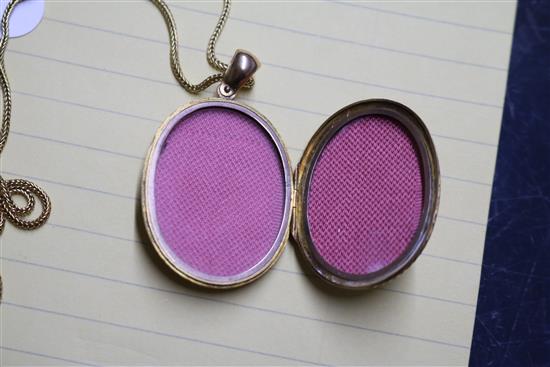 A Victorian engraved yellow metal oval locket, on a 9ct gold chain, locket 37mm.